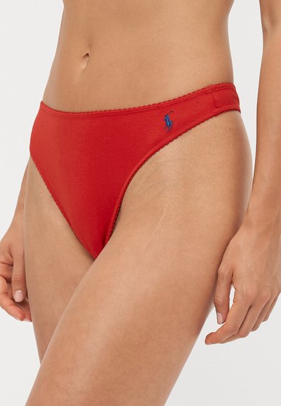 Sarkans kokvilnas bikini apakšbikses ar gludu tekstūru, ar zilu izšūtu logotipu un viļņotu malu gar jostasvietu.