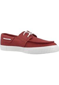 Zapatilla de lona roja con punta redonda, suela de goma blanca y cordones blancos contrastantes. Textura suave con un diseño simple y casual.