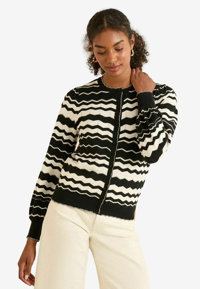 Czarny i biały kardigan w zygzaki z okrągłym dekoltem, bufiastymi rękawami i zapięciem na guziki; materiał o fakturze dzianiny.