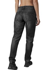 Jeans de denim negro con corte ajustado, con una cintura de altura media, diseño de cinco bolsillos y costura característica en los bolsillos traseros.