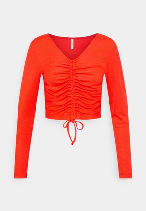 Top rosso a maniche lunghe con scollo a V, caratterizzato da tessuto arricciato, design corto e dettaglio a fiocco all'orlo. Tessitura liscia.