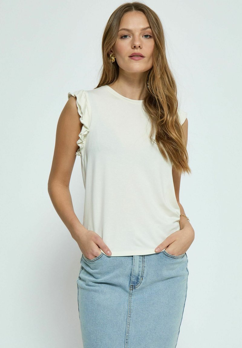 Crème korte mouw top met ruches op de schouders; zacht, lichtgewicht stof; gecombineerd met een lichtblauwe denim rok.