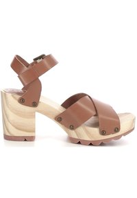 Sandali con tacco in pelle marrone, con cinturini incrociati, tacco a blocco in legno, suola rigata e dettagli in hardware bronzo.