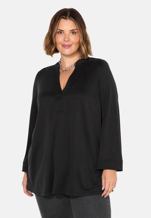 Tunika nera con scollatura a V e maniche lunghe. Realizzata in tessuto morbido con una vestibilità rilassata e dettagli di pieghe sottili all'escafandro.