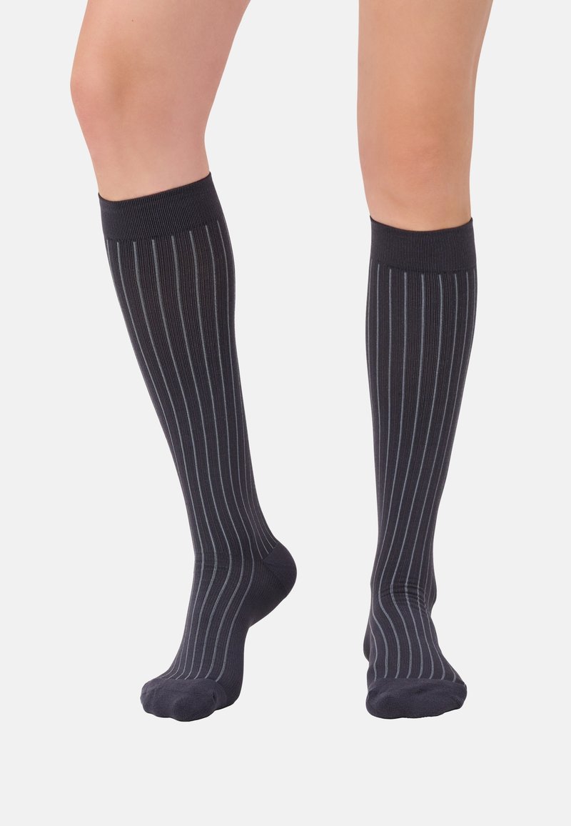 Kniestrümpfe in dunkelblau mit dünnen vertikalen weißen Streifen. Hergestellt aus einem glatten, elastischen Stoff und mit gerippten Bündchen am oberen Ende.