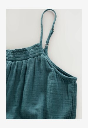 Miętowy lniany top z marszczonymi detalami, regulowanymi ramiączkami spaghetti i luźnym krojem. Widoczne szwy i miękkość materiału.