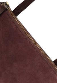Bordeaux ruskinds taske med et brunt læderrem, der har en guldlås, og fremhæver en glat tekstur og minimalistisk design.