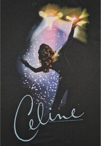 Musta t-paita, jossa on värikäs graafinen kuva hahmosta, johon liittyy pyöriviä valoja ja säihkettä. Teksti "Celine" sinisellä kursiivilla alareunassa.