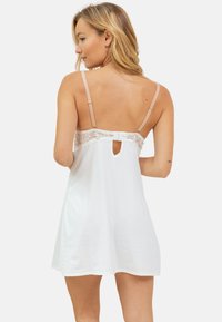 Nuit blanche avec des détails en dentelle au dos, bretelles nude ajustables, ouverture en forme de clé et tissu doux. Longueur mi-cuisse.