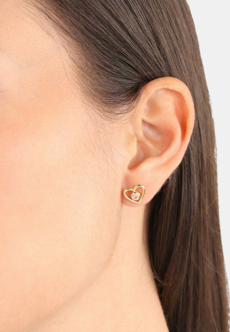 Orecchini a perno a forma di cuore in oro con un gemma rosa centrale. Finitura in metallo liscia con design a outline aperto, adatti per un uso quotidiano.