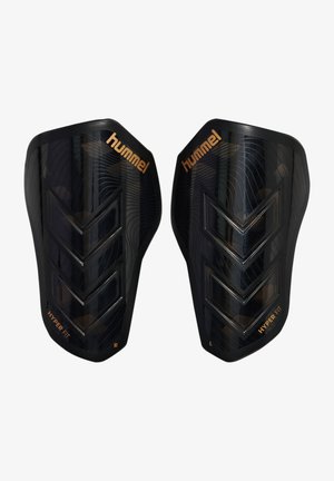 Zwarte Hummel Hyper Fit scheenbeschermers met verhoogde chevronpatronen, aangeduid voor links en rechts, voor voetbalsbescherming.
