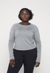 Gray long-sleeve top with a textured pattern and raglan sleeves, paired with black fitted pants. Features soft fabric and a crew neckline.