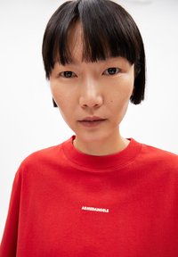 Rotes Baumwoll-Sweatshirt mit Rundhalsausschnitt und gerippten Bündchen. Mit weißem Text "ARMEDANGELS" auf der Brust. Glatte Textur, lässige Passform.