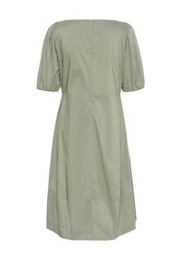 Olivnozeleni bombažni plašč z napihnjenimi rokavi, okroglo ovratnikom, zadrgo zadaj in A-linijo; gladka tekstura in minimalističen dizajn.