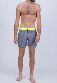 Shorts de bain pour hommes en bleu marine avec un motif géométrique, dotés d'une taille élastique jaune vif et d'un cordon de serrage, fabriqués à partir d'un matériau léger.