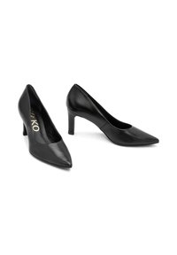 Zapatos de tacón alto de cuero negro con un diseño de punta afilada y un tacón de altura media, que presentan una textura suave y un estilo minimalista.
