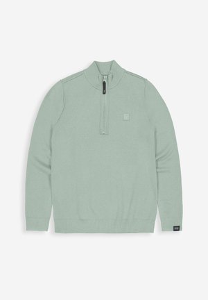 Hellgrüner Strickpullover mit hohem Kragen, halbem Reißverschluss, gerippten Bündchen und einem kleinen Logo-Patch auf der linken Brust.