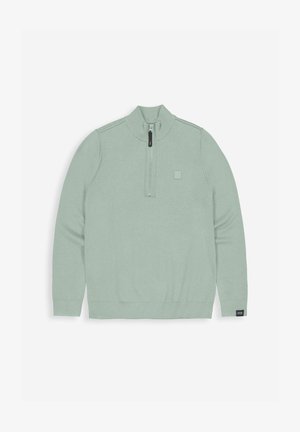 Hellgrüner Strickpullover mit hohem Kragen, halbem Reißverschluss, gerippten Bündchen und einem kleinen Logo-Patch auf der linken Brust.