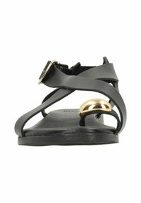 Black leather sandal with crossed straps, flat sole, metal accent, and buckle detail. Elegant design with a minimalist aesthetic.