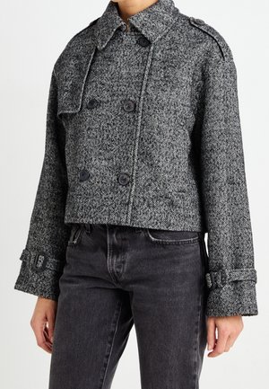 Szara dwurzędowa kurtka w jodełkę, skrócona, z czarnymi guzikami, pagonami na ramionach i regulowanymi mankietami na klamry, noszona z ciemnoszarymi dżinsami.