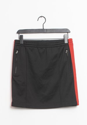 Zwarte rok met rode zijpanelen, elastische tailleband en ritssluitingen, hangend aan een zwarte kledinghanger tegen een witte achtergrond.