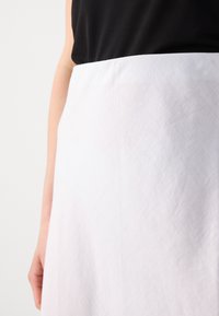 White linen skirt with a textured finish, displaying a smooth fabric draping from the waist and a minimal design with no visible hardware.
