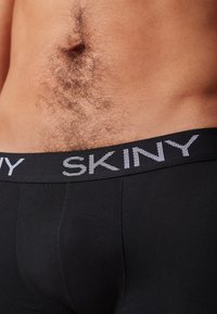 Sorte herres boxer briefs med en struktureret linning, der har brandnavnet "SKINY" i sølv. Materialet ser glat ud med en tætsiddende pasform.