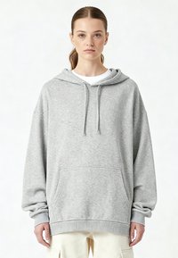 Felpa oversize grigio chiaro realizzata in morbido misto cotone. Presenta un cappuccio con coulisse, tasca frontale, polsini e orlo a coste.