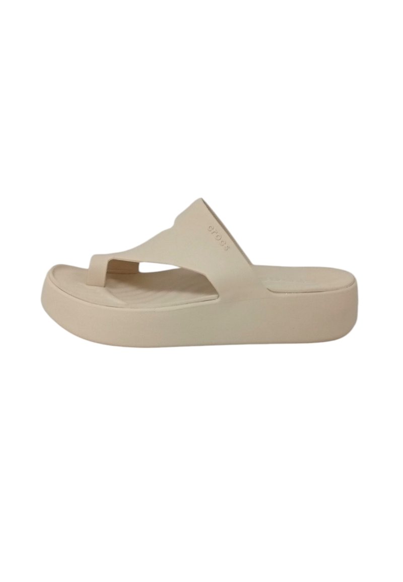 Sandal in beige a infradito con una suola spessa e testurizzata, design minimalista e un cinturino superiore a forma di V. Materiale liscio con un marchio discreto.