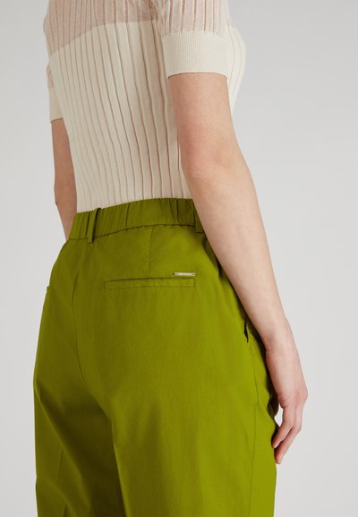 Pantalones verdes con una cinturilla elástica y texturizada. Bolsillos laterales y un pequeño acento de metal plateado encima del bolsillo trasero.