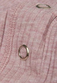 Růžová texturovaná látka s vertikálním žebrováním. Obsahuje kovový kroužek jako ozdobu, prošité okraje a měkký pletený vzhled.