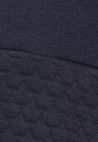 Tela de color marino que presenta dos texturas: una sección superior lisa y una sección inferior texturada con un sutil patrón de panal.