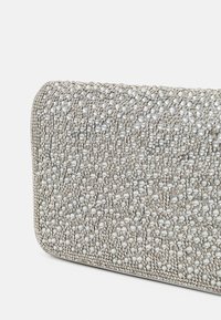 Pochette en argent ornée de cristaux avec une surface texturée, présentant des perles arrondies et une forme rectangulaire lisse. Design minimaliste.