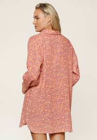 Losse, langmouwige shirt in het roze met luipaardprint; beschikt over een kraag en knoopsluiting, en een zachte, textuurstof.