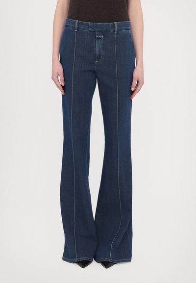 Donkerblauwe uitlopende jeans met een gladde denim textuur, voorzien van contrasterende stiksels, een ritssluiting aan de voorkant en een middelhoge taille.