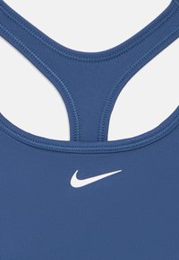 Μπλε ναυτικό αθλητικό τοπ με ψηλό λαιμό, σχεδιασμό racerback και λευκό λογότυπο Nike στο στήθος. Λείο, ελαστικό ύφασμα με ραφές.