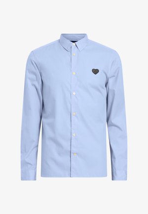 Lichtblauwe longsleeve shirt van katoen, met een button-down kraag en een zwart hartvormig geborduurd detail op de borst.