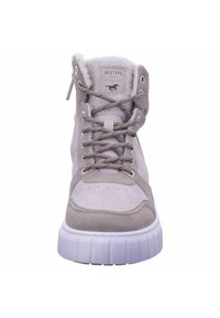 Bottes montantes beiges avec une tige en daim, semelle en caoutchouc blanc, col rembourré, œillets en métal et doublure douce visible de la vue de dessus.