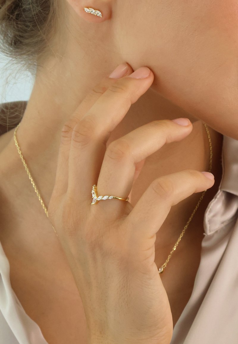 Gold jewelry set featuring a slender ring with marquise-cut clear stones, matching stud earrings, and a delicate chain necklace.