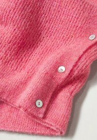 Vaaleanpunainen neulepaita, jossa on pehmeä, pörröinen pinta, kolme valkoista nappia hihassa ja löysä neulekuvio, korostaen sen rentoa ilmettä.