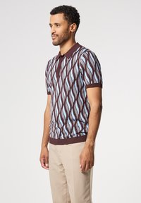 Polo de manga corta en marrón y azul claro con un patrón de olas, que presenta un cuello y puños acanalados, elaborado con una tela de punto texturizada.