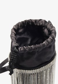 Schwarze Satin-Zugtasche mit silberner Kettenfringe am Boden. Verfügt über einen gerafften oberen Teil und geflochtene Träger für ein einfaches Tragen.