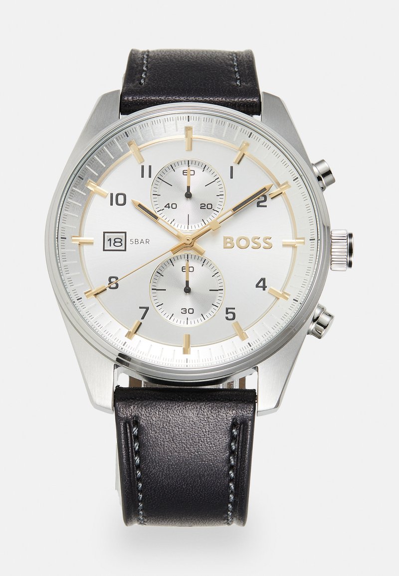 Relógio cronógrafo prateado com pulseira de pele preta, mostrador branco, detalhes em dourado, data exibida às 6 horas e dois submostradores para segundos e minutos.