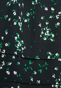Tela de vestido floral con un fondo negro y patrones de flores blancas y verdes. Textura suave con detalles de diseño en capas.