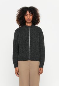 Sweater tricotado texturizado em cinza escuro, com colarinho alto e zíper frontal completo. Apresenta punhos e bainha canelados, com um design ligeiramente encurtado.