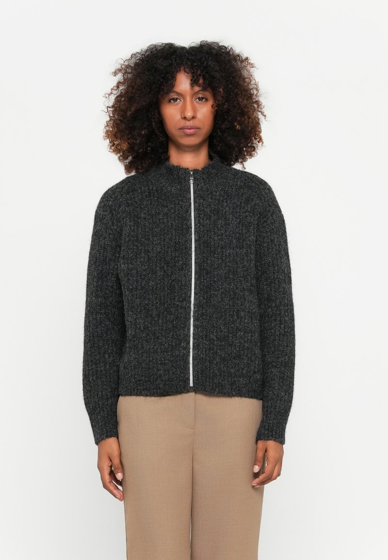 Sweater tricotado texturizado em cinza escuro, com colarinho alto e zíper frontal completo. Apresenta punhos e bainha canelados, com um design ligeiramente encurtado.