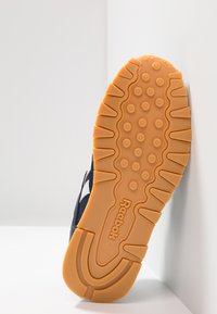 Suola di sneaker Reebok con base in gomma naturale, caratterizzata da un motivo testurizzato di bump circolari e scanalature per una migliore aderenza.