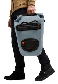 Lichtblauwe waterdichte tas met gestructureerd oppervlak, zwarte hardware en oranje accenten. Handvast met bovenste riemen, cilindervormig.