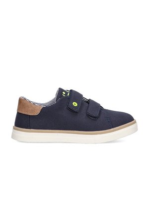 Zapatos de lona azul marino con detalles en cuero marrón, suela blanca y correas ajustables de Velcro. Presentan un forro interior a rayas y un diseño ligero.
