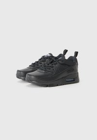 Sneakers en cuir noir avec des superpositions texturées, bout arrondi, col rembourré et unité d'air visible dans le talon. Présente une fermeture à lacets et une languette.